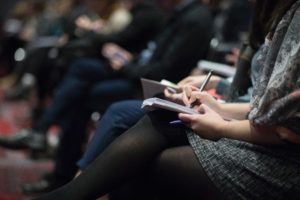 Image of woman taking notes at an event or conference