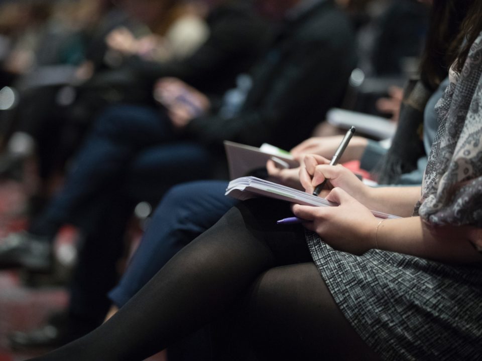 Image of woman taking notes at an event or conference
